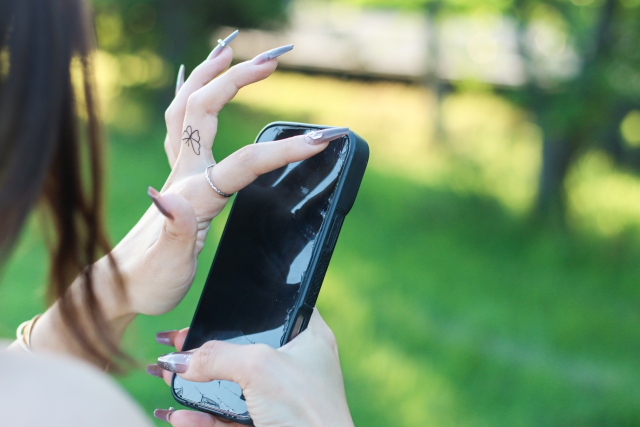 スマホのフィルムを触る女性